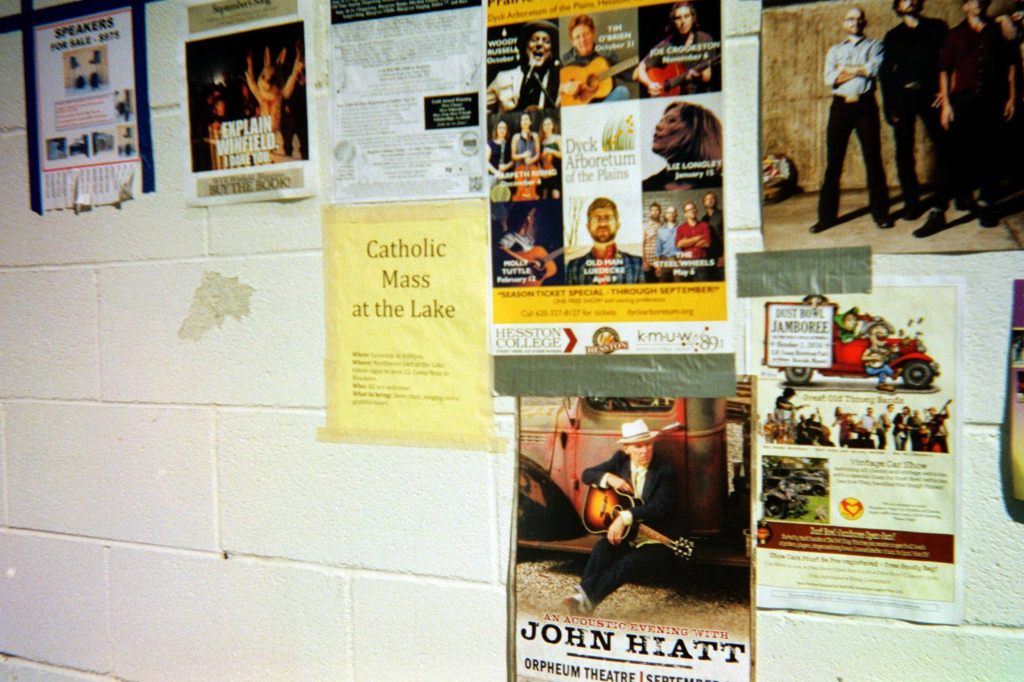 Grainy photo of cement wall covered in event posters.